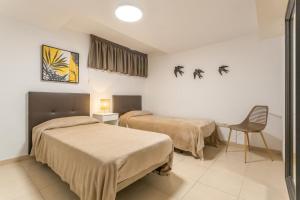 una habitación de hotel con dos camas y una silla en Obsidian Peridotita Adeje, en Adeje 16 fotos más
