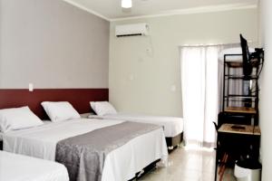 Una habitación de hotel con dos camas y una ventana. en Pousada Apatej, en Peruíbe