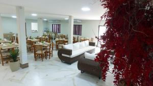 un restaurante con sofá, mesas y flores rojas en Pousada Apatej, en Peruíbe