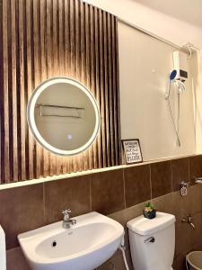 a bathroom with a sink and a mirror and a toilet at Rafaels Staycation at Arezzo in Davao City