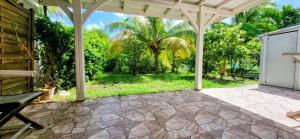 an empty patio with a white pergola and trees at les jardins de sainte Anne in Sainte-Anne