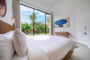 a bedroom with a large white bed and a large window at Bali Bliss - New 2BR Villa with Private Pool & Green Garden Views in Ungasan +8 photos