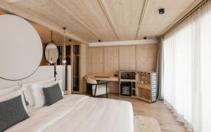 セルヴァ・ディ・ヴァル・ガルデーナにあるMuliné Lodgeの白いベッドとテーブルのある寝室