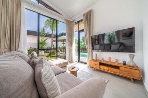 a living room with a couch and a large window at Bali Bliss - New 2BR Villa with Private Pool & Green Garden Views in Ungasan