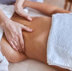 Una mujer acostada en una cama con las manos sobre el estómago. en Pousada Spa Peruíbe, en Peruíbe