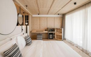 セルヴァ・ディ・ヴァル・ガルデーナにあるMuliné Lodgeの白いベッドと大きな窓のある寝室 +73枚の写真