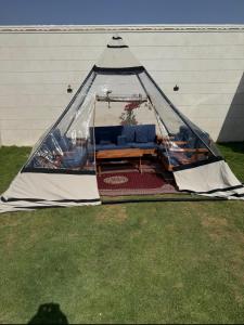 una tienda de campaña con un sofá dentro sobre el césped en شاليه داله العماريه2 بالكامل لك وأجواء ممتعه, en Al ‘Ammārīyah