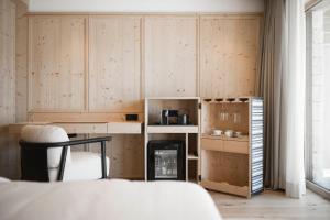 セルヴァ・ディ・ヴァル・ガルデーナにあるMuliné Lodgeの木製のキャビネット、テーブル、椅子が備わる客室です。