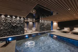 a swimming pool in a room with a stone wall at Muliné Lodge in Selva di Val Gardena