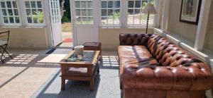 a brown leather couch sitting in a room with a table at Suite Majorelle du Château in Gaillan-en-Médoc +19 photos