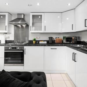 eine Küche mit weißen Schränken und einem Herd mit Backofen in der Unterkunft Stylish Penthouse - 2 King Size Beds - Parking - Private Terrace 1401M in Birmingham