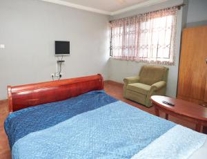 a bedroom with a bed and a chair and a table at ODeTTe GUEST HOUSE in Kumasi