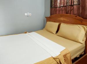 a bed with a wooden headboard and pillows at ODeTTe GUEST HOUSE in Kumasi