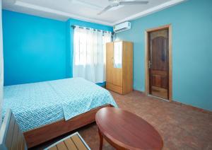 a blue bedroom with a bed and a wooden cabinet at ODeTTe GUEST HOUSE in Kumasi