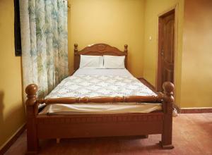 a bed in a bedroom with a wooden bed frame at ODeTTe GUEST HOUSE in Kumasi