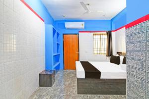 a bedroom with a bed and blue walls at Hotel O New Cuttack Guest House in Cuttack