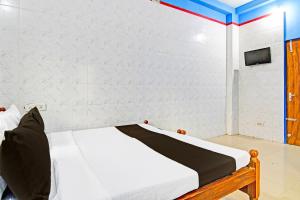 a bed in a room with a white wall at Hotel O New Cuttack Guest House in Cuttack