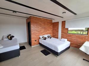 a bedroom with two beds and a brick wall at Suit Encanto Dorado in Guatavita +10 photos
