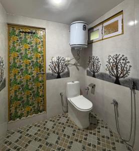 a bathroom with a toilet and a painting on the wall at Hotel Crescent in Srinagar