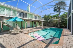 a swimming pool with a umbrella and chairs and a house at The Turtle Nest in Sanibel