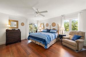 a bedroom with a bed and a chair and a ceiling fan at The Turtle Nest in Sanibel +65 photos