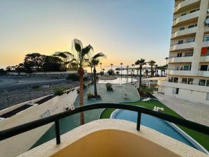 a view of a resort with a pool and palm trees at Apartment in front of the ocean in Los Cristianos