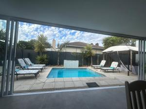 a patio with a pool and chairs and an umbrella at Ocean Whisper Room 6 minutes away from the beach in Cape Town