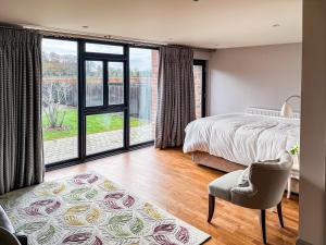 a bedroom with a bed and a chair and large windows at Valentines Cottage - Uk48509 in Kirk Hammerton