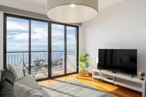 un soggiorno con TV e una grande finestra di Blue Horizon Apartment by An Island Apart a Nogueira