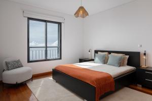 una camera da letto con un letto, una finestra e una sedia di Blue Horizon Apartment by An Island Apart a Nogueira