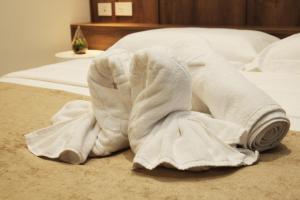 a white towel laying on a bed at A Gallery Hotel in Shkodër +26 photos