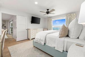 a white bedroom with a bed and a television at Seaside Retreat in Santa Rosa Beach +55 photos