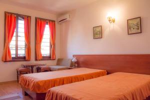 a room with two beds and a chair and windows at Sivrieva House in Zlatograd