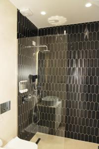 a bathroom with a shower with a black tiled wall at A Gallery Hotel in Shkodër