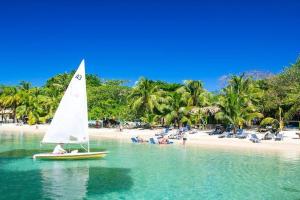 un velero en el agua en una playa en West end inn, en Roatan