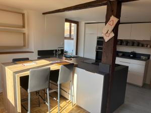 a kitchen with a counter and some chairs in it at La Belle Mélusine in Bergheim