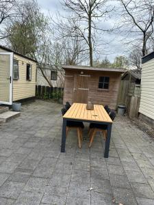 a wooden table sitting on a patio with two chairs at Prachtige Chalet op Camping It Wiid in Earnewâld +1 photo