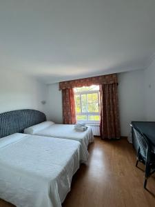 two beds in a room with a window at Hostal Chocolate & Menta Redondela in Redondela