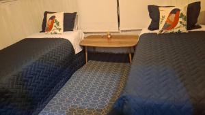 two beds in a room with a wooden table between them at Alojamiento MI MOMMA in Osorno