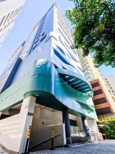 ein hohes Gebäude mit einer Fassade aus Blau und Glas in der Unterkunft Stay Inn com Vista Mar Parcial, Piscina, opção de estacionamento na quadra da praia in Santos