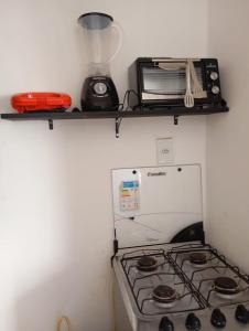 una cucina con piano cottura e forno a microonde su una mensola di Kitnet no centro da vila a Mata de Sao Joao
