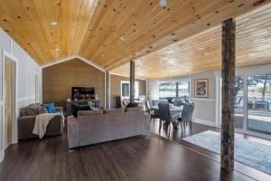 a living room with a wooden ceiling and a dining room at Rustic Lakefront Cottage with Fire Pit & Scenic Views in Brechin