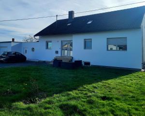 a white house with a car parked in a yard at Wohnung in Windhagen Nähe A3 in Windhagen