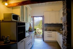 a kitchen with white cabinets and a large window at Tenuta Lonciano in Gualdo