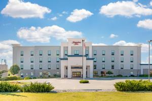 a white building with a flag in front of it at Hampton Inn Junction City in Junction City