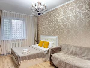 a bedroom with a bed and a couch and a chandelier at тёплое гнёздышко in Astana