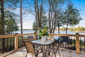 a table and chairs on a deck with a view of the water at Rustic Lakefront Cottage with Fire Pit & Scenic Views in Brechin