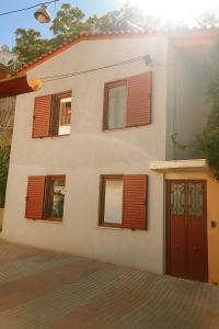 a house with brown shuttered windows and a door at Evanthia maisonette in Chalkida