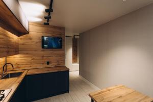 a kitchen with wooden walls and a tv on the wall at Luxury Apartment Lushpy Avenue - Hotel Standard in Dobrovelychkivka