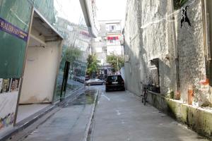 an alley with a car parked next to a building at A Gallery Hotel in Shkodër